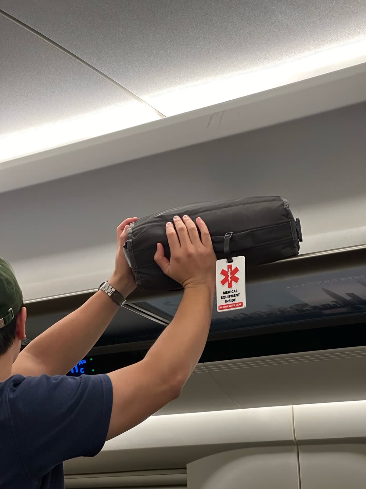 Traveler lifting a carry-on bag with a medical ID luggage tag